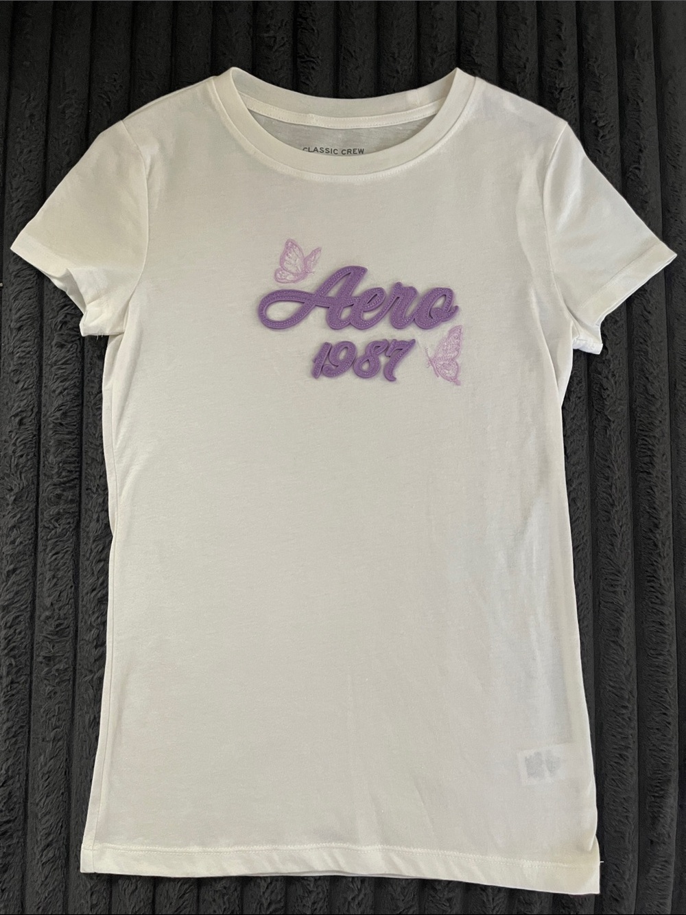 1987 Women’s White Graphic Tee with Purple Script